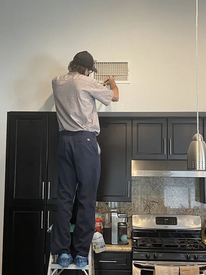 Technician inspecting an air vent during HVAC service in Highland Park